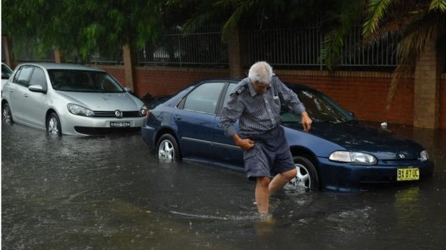 A man wades through floodwater in Sydney, Australia