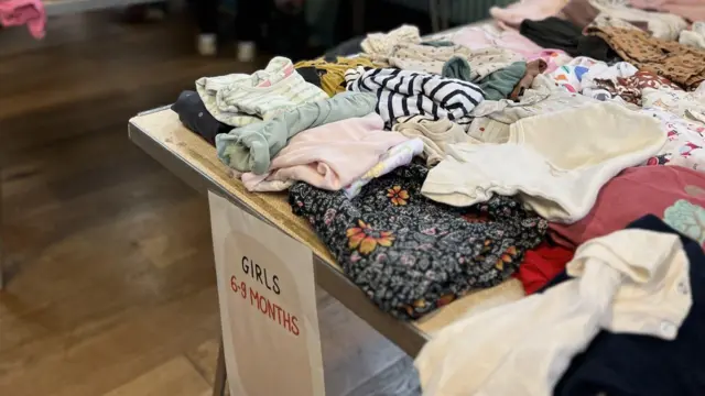 Una mesa llena de ropa infantil en la tienda de intercambio.