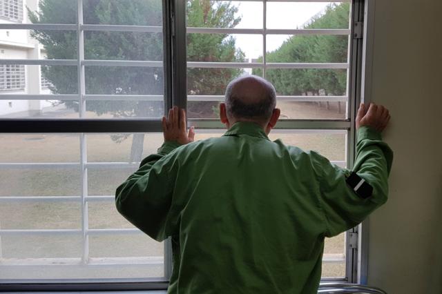 Prisioneiro japonês olhando pelas grades da prisão