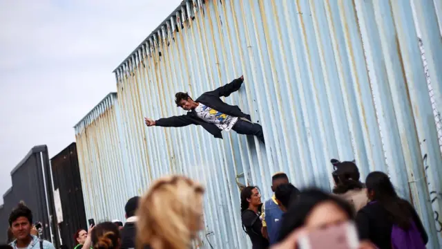 Un migrante protesta junto a la valla de la frontera con Estados Unidos