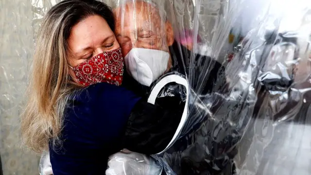 В бразильском Сан-Паулу женщина обнимает своего 82-летнего отца через "обнимательный занавес"