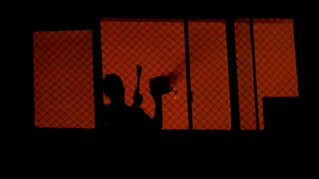 Persona tocando una cacerola en protesta desde una ventana.