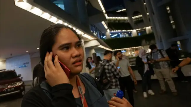 A woman uses a phone as she leaves an office building, following an earthquake hit in Jakarta, Indonesia, August 2, 2019