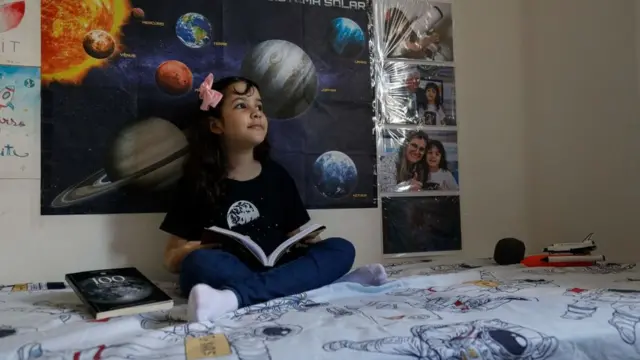 Nicole reads in her room full of science posters