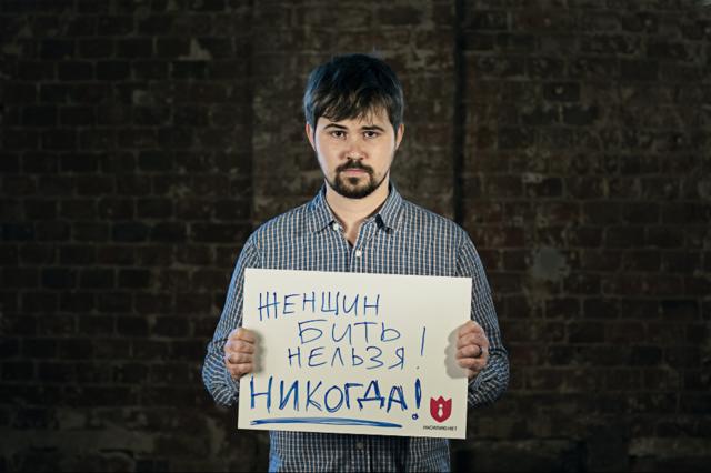 Musisi Vasya Oblomov membawa poster bertuliskan, "Dilarang memukul perempuan!"