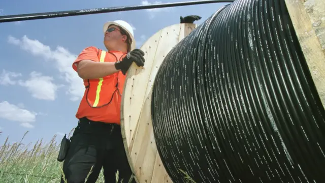 Trabalhador com rolo de fibra ótica.