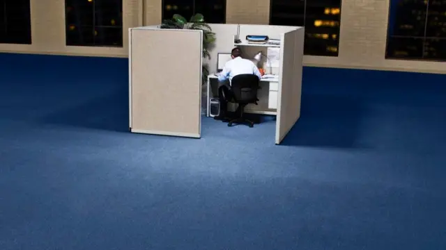 Una persona en un cubículo solitario en una oficina vacía