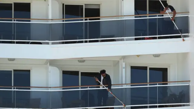 Dos hombres limpian los balcones del crucero.