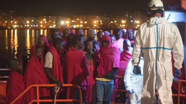 Мигранты высаживаются со спасательных лодок в порту Малаги