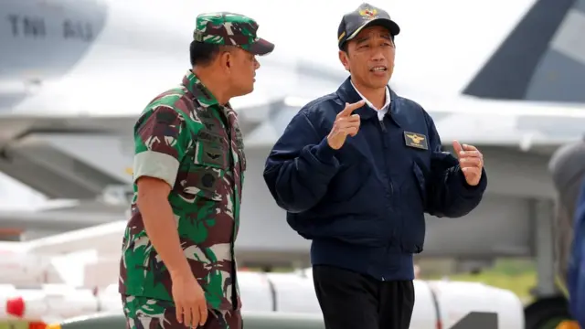 Indonesia"s President Joko Widodo talks with Military Chief Gatot Nurmantyo as they walk past fighter jets and weapons during a military exercise on Natuna Island