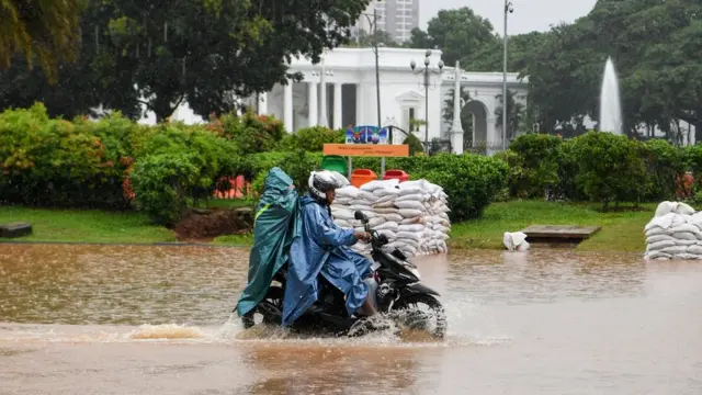Pengendara sepeda motor melintasi banjir di Jalan Medan Merdeka Barat, Jakarta, Minggu (2/2/2020).