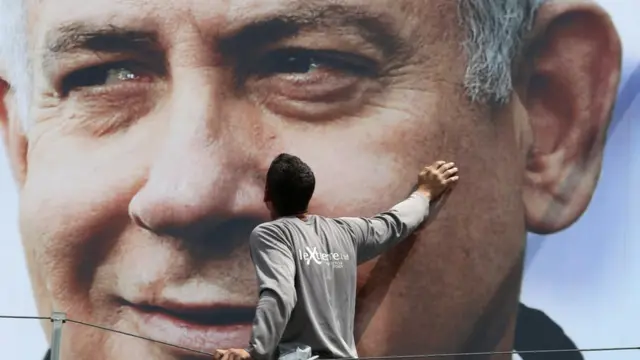 عامل يثبت صورة إعلانية لنتنياهو خلال الحملة الانتخابية الأخيرة