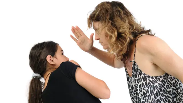 una mujer levantándole la mano a una niña