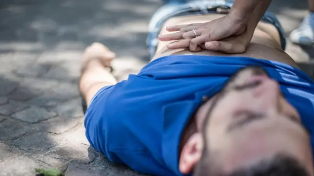 شاب متمدد على الأرض وآخر يحاول انقاذه بالضغط على صدره