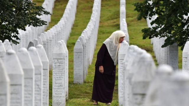 A Srebrenica survivor kisses her son's gravestone