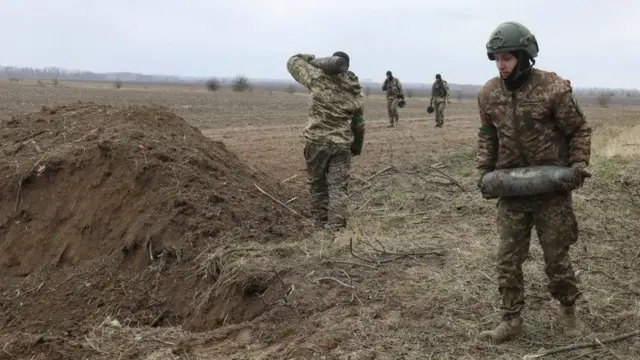 Military sappers carry unexploded shells left after Russia"s invasion near the village of Motyzhyn, in Kyiv region, Ukraine April 10, 2022