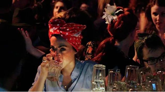 Una mujer toma agua en un bar.