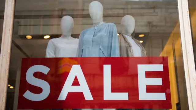 Vitrina de almacén de ropa con aviso de "Sale".