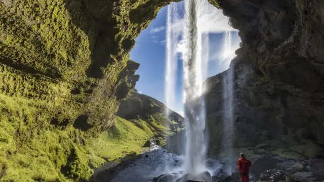Mujer en una cueva en la que cae una catarata