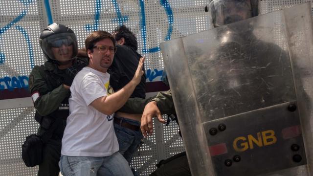 Fredy Guevara, vicepresidente de la Asamblea Nacional, se puso en el medio entre un manifestante y un funcionario de seguridad para evitar que lo detuviera.