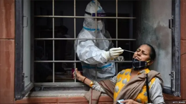 कोविड-19 के टेस्ट के लिए एक महिला का स्वैब लेता स्वास्थ्यकर्मी