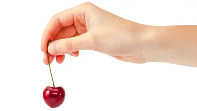 Mano sosteniendo una cereza.