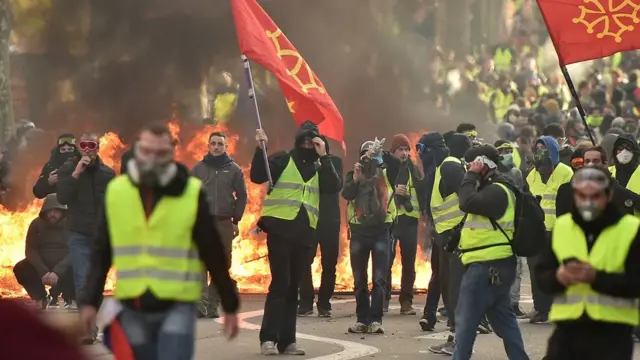 Protestors wearing yellow vests (gilets jaunes) wave Occitan flags during a demonstration against rising costs of living they blame on high taxes in Toulouse, southern France, on December 8, 2018.