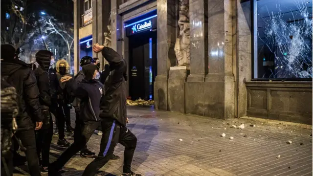 Unos manifestantes lanzan piedras contra una sucursal bancaria.