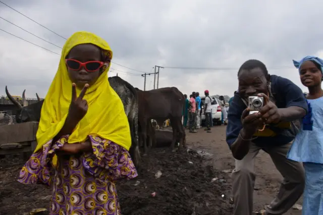 A girl wearing sunglasses makes the V-sign at the camera.