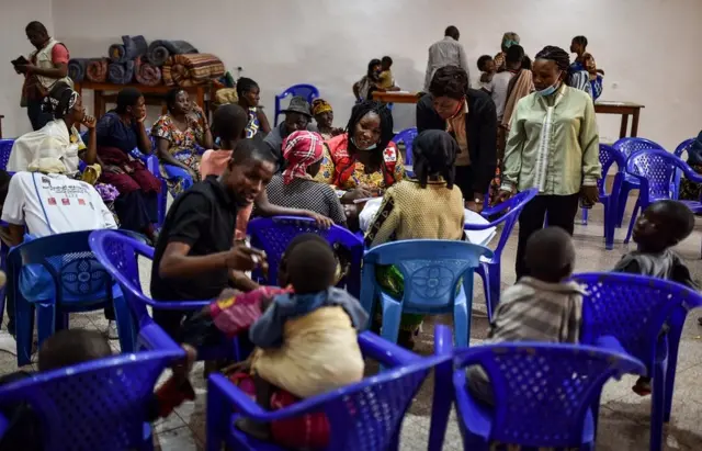 People sitting on plastic chairs.