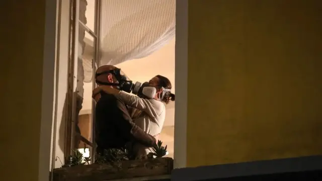 زوجان يرتديان الأقنعة يتعانقان أثناء التصفيق اليومي للعاملين بقطاع الرعاية الصحية في نيس في مارس/آذار 2020