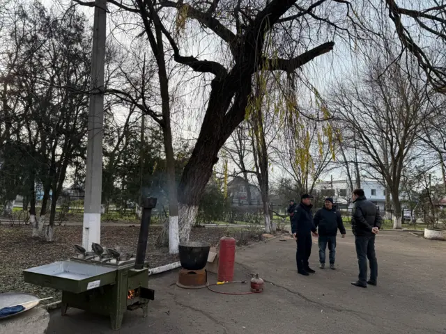 Троє чоловіків біля польової кухні