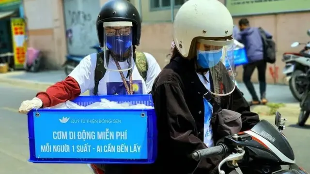 Tình nguyện viên của quán cơm Nụ Cười đi phát được trang bị khẩu trang, tấm kính chắn phía trước để giảm rủi ro.