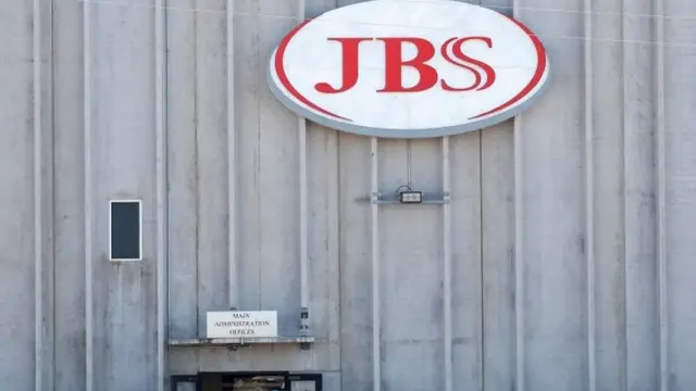 Employees walk around with face masks at the JBS USA meat packing plant
