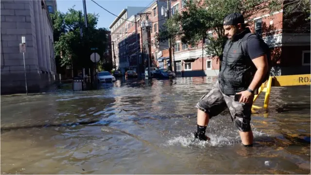 A man walks through a flooded street the morning after the remnants of Hurricane Ida drenched the New York City and New Jersey area on September 2, 2021 in Hoboken, New Jersey.