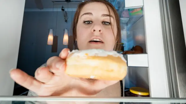 Mulher pegando bolo da geladeira