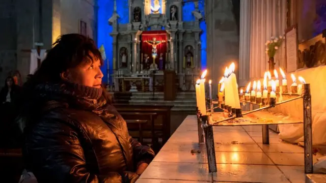Mujer reza en catedral en Perú