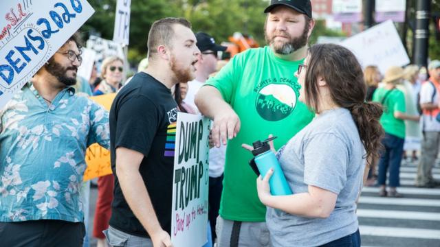 美国新罕布什尔州曼彻斯特一场声援特朗普集会会场外绿衣男子尝试调停在吵架的支持特朗普黑衣男子（左）与反特朗普灰衣女子（女）（15/8/2019）