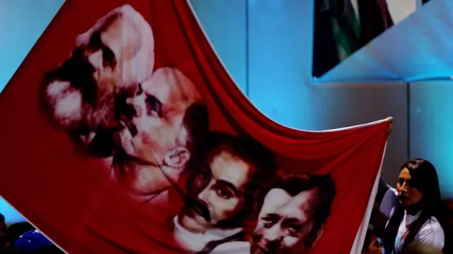 Una mujer muestra un cartel con la imagen de algunos de los referentes ideológicos de las FARC, como Marx y Lenin, durante el congreso de la Habana.