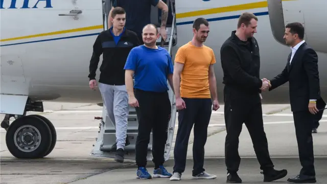 пленные сходят с трапа, Зеленский их приветствует