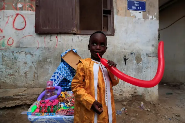 A boy tries to inflate a balloon.