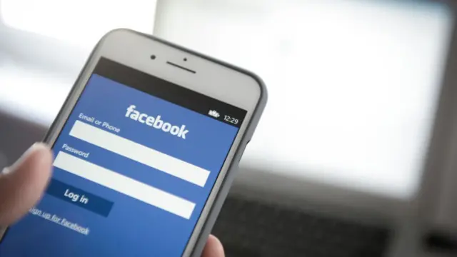 Pantalla de celular con la página de inicio de Facebook.