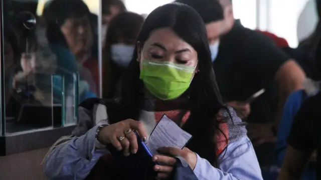 Seorang penumpang kapal dari Malaysia memakai masker berjalan menuju Terminal Kedatangan Pelabuhan Internasional PT Pelindo I Dumai di Dumai, Riau, Jumat (7/2/2020).