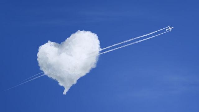Imagem de avião atravessando nuvem em formato de coração