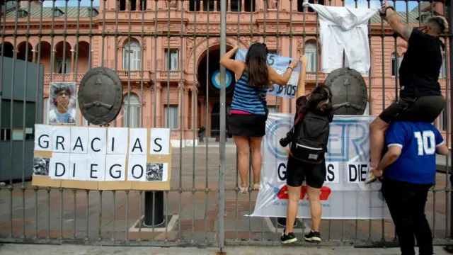 As pessoas colocam bandeiras e cartazes na frente da Casa Rosada