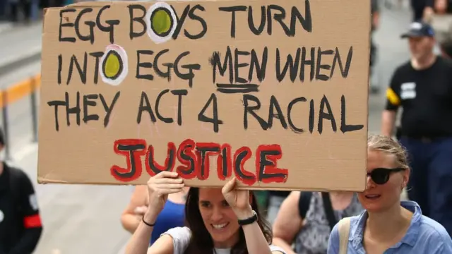 Seorang pemrotes dalam aksi menuntut mundurnya Senator Australia, Fraser Anning, dan mengajak bersatu melawan rasisme dan Islamofobia, membawa papan kertas yang merujuk pada aksi Egg Boy atau pemuda asal Melbourne, Will Connolly, yang melemparkan telur ke politisi Fraser Anning.