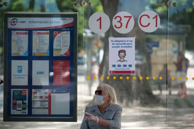 Mujer espera al autobús con la mascarilla puesta en Málaga, España.