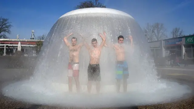 Visitors of the 'Sonnenbad' open-air public swimming pool take a shower at a water mushroom during the opening of the season on February 26, 2016 in Karlsruhe, southern Germany