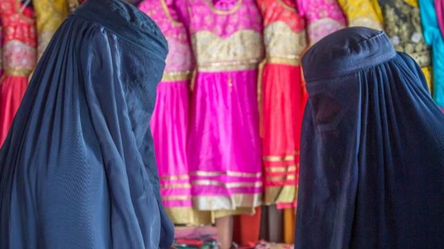 Женщины в паранджах выбирают одежду в магазине в афганской провинции Бадахшан