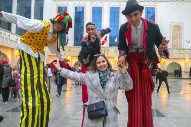 Mgeni akipiga picha na vinyago wenye miguu mirefu kwenye Tamasha la Sanaa la Vikaragosi la Carthage mjini Tunis, Tunisia - Jumamosi tarehe 19 Machi 2022